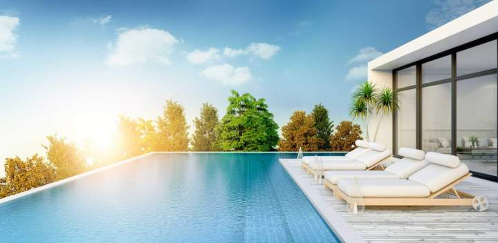 Une superbe piscine à débordement avec une vue panoramique sur un paysage verdoyant, sous un ciel bleu clair.